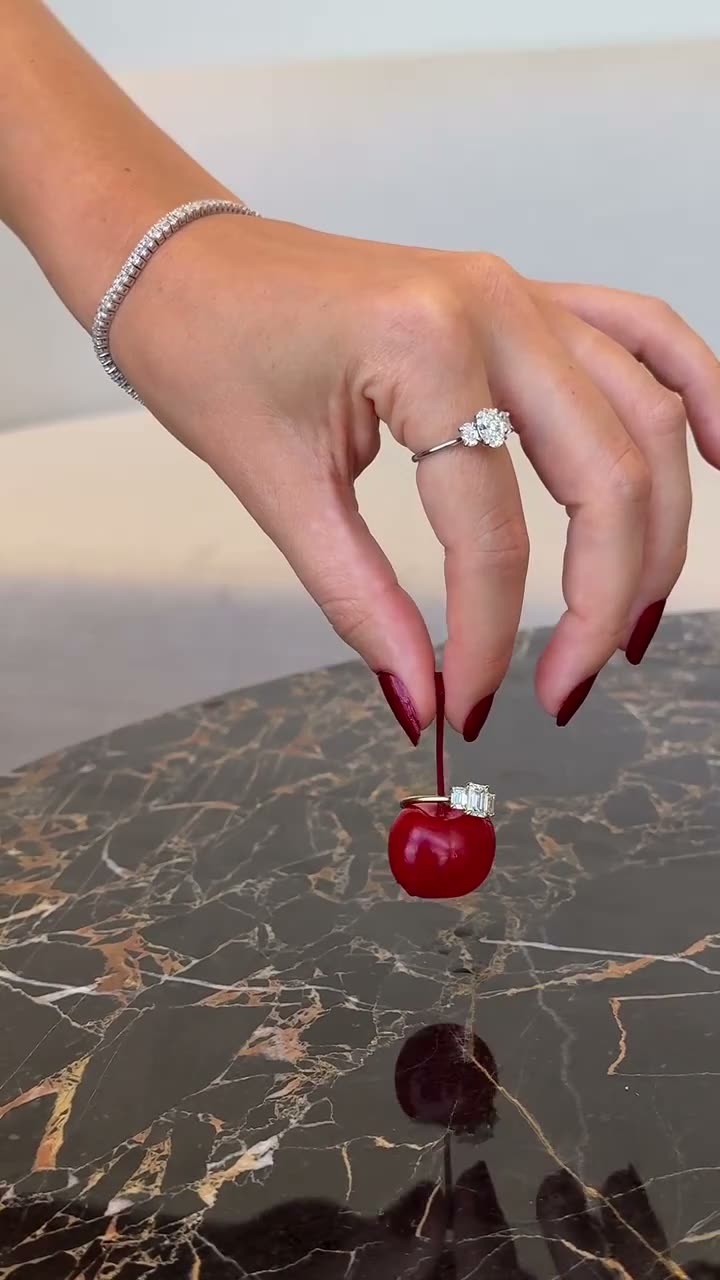 A diamond ring lifted from a cherry on black marble