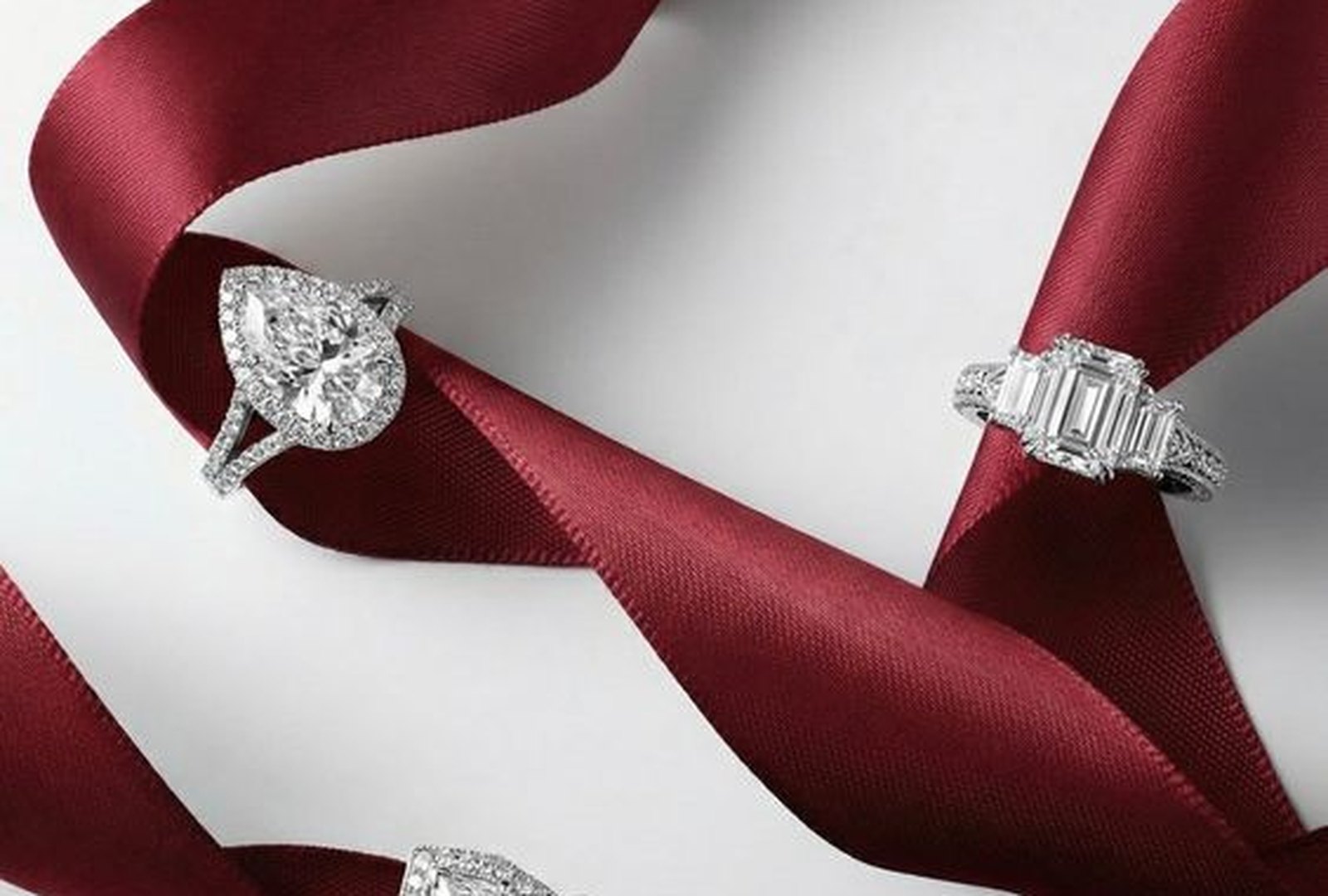 Four diamond rings laid on burgundy silk ribbon