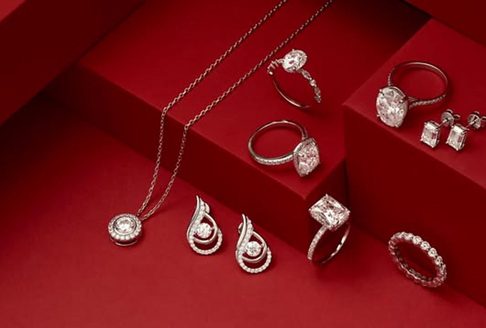 Diamond rings, earrings and a pendant arranged on red blocks